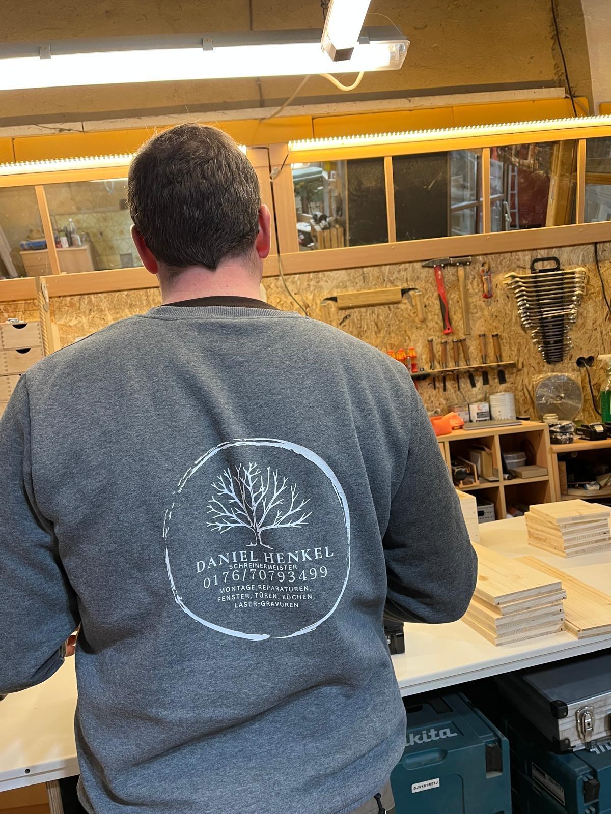 Daniel Henkel mit Firmen-Pullover in der Werkstatt — Schreinermeister aus Tegernheim